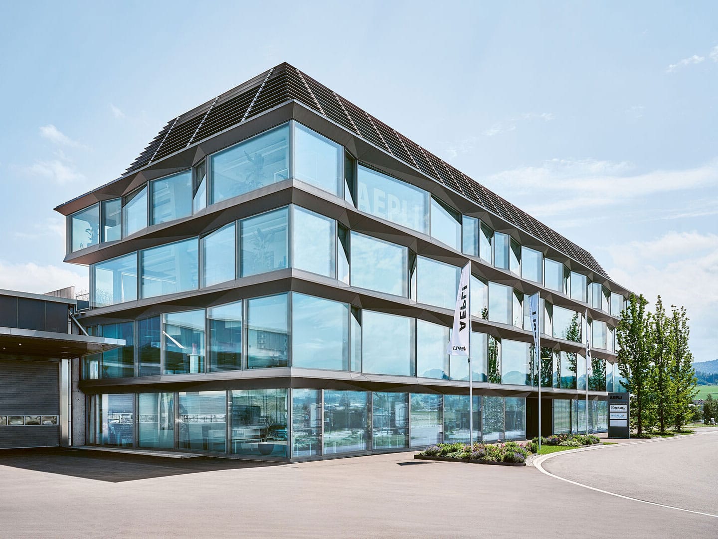Modern multi-story office building with extensive glass windows and sleek architectural design under a clear blue sky.