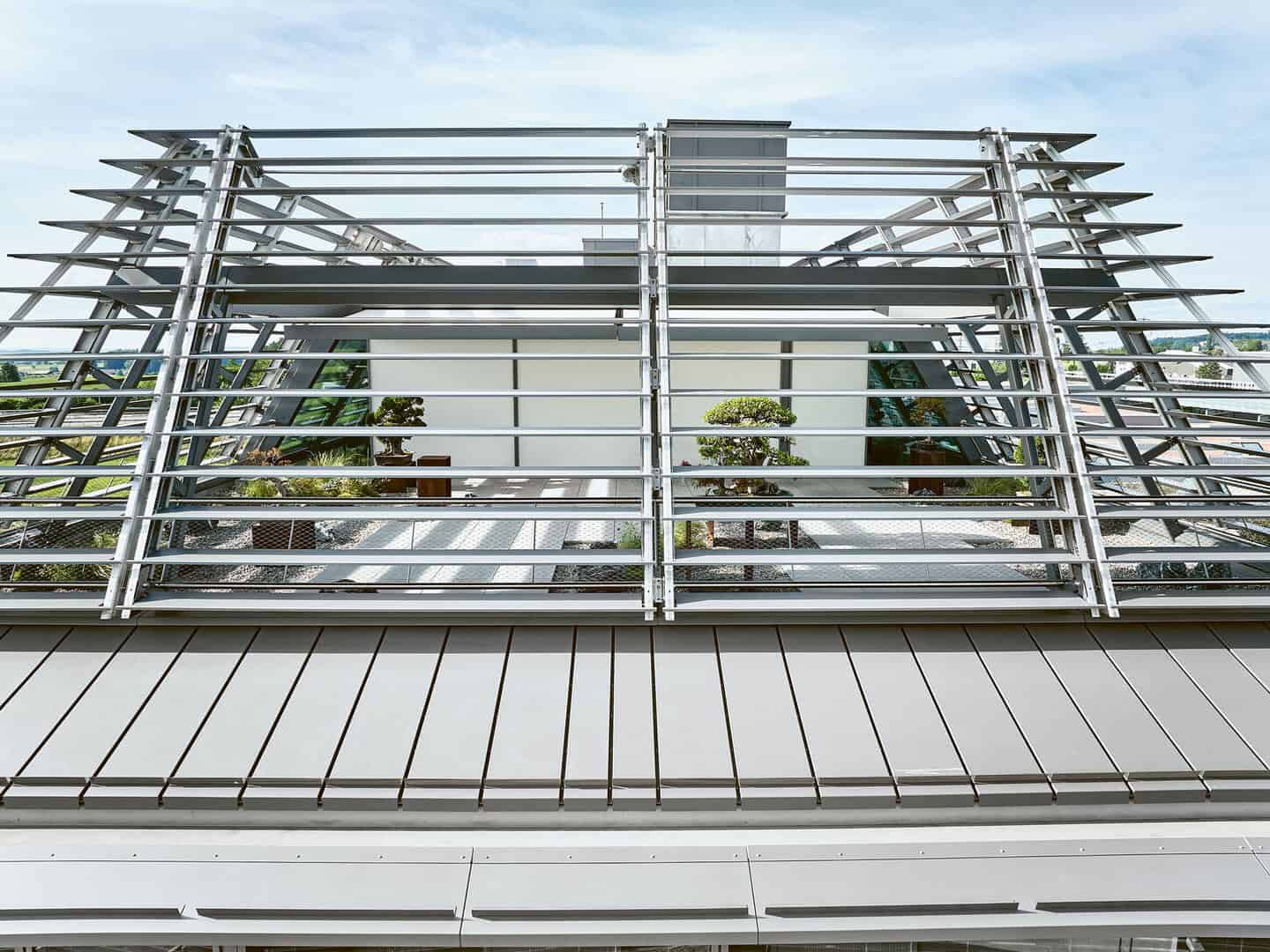 Modern building with sleek metal exterior, open window louvers, and visible rooftop ventilation system, highlighting contemporary architectural design and energy-efficient features.