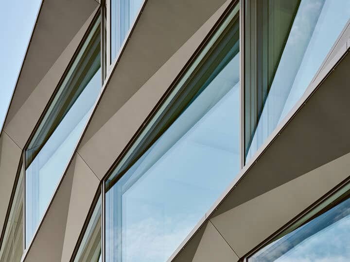 Shiny modern building facade with large glass windows and angular architectural design.