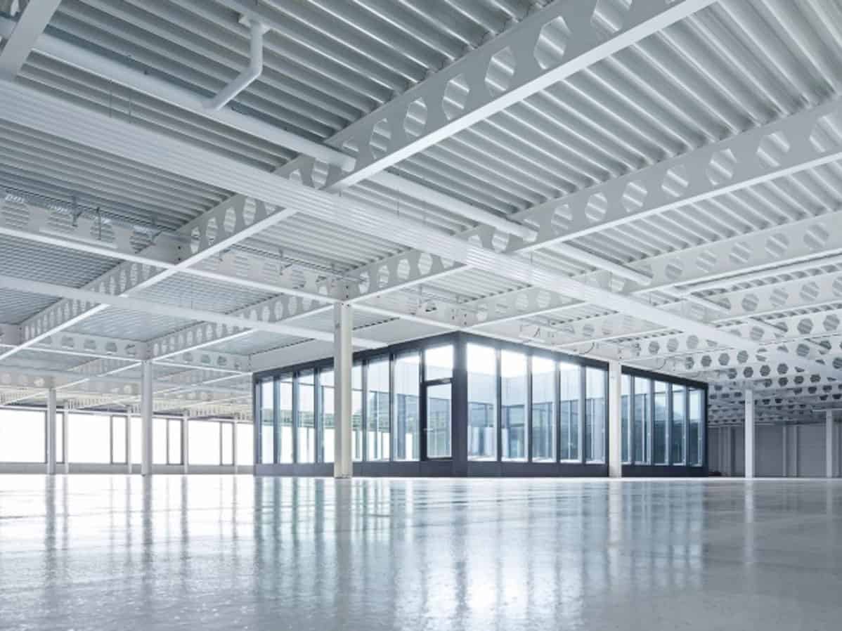Elevated view of a modern, spacious commercial interior with a metal grated ceiling and glass walls allowing natural light to fill the space.